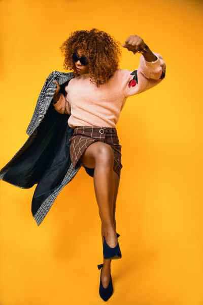 woman in peach color and red floral sweatshirt holding gray jacket