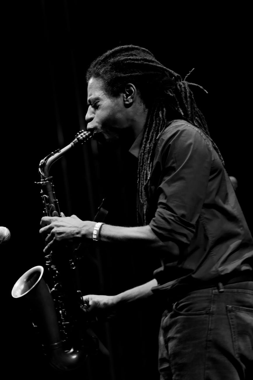 monochrome photo of man playing saxophone